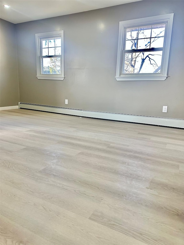 spare room with light wood finished floors and a baseboard heating unit