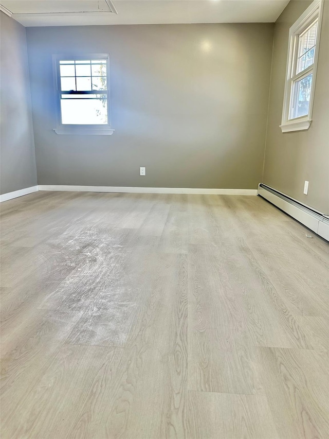 spare room with attic access, a baseboard radiator, and baseboards