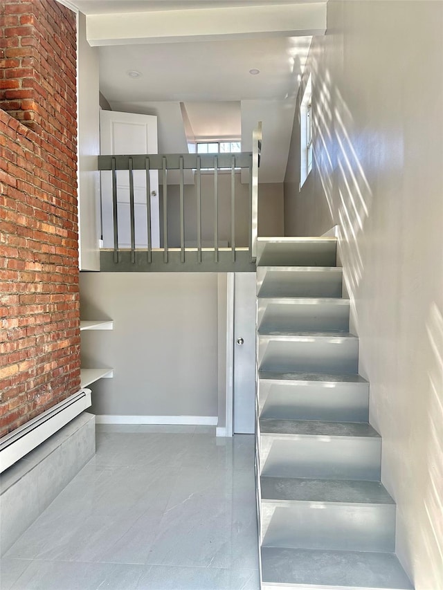 stairs with brick wall, baseboard heating, and baseboards