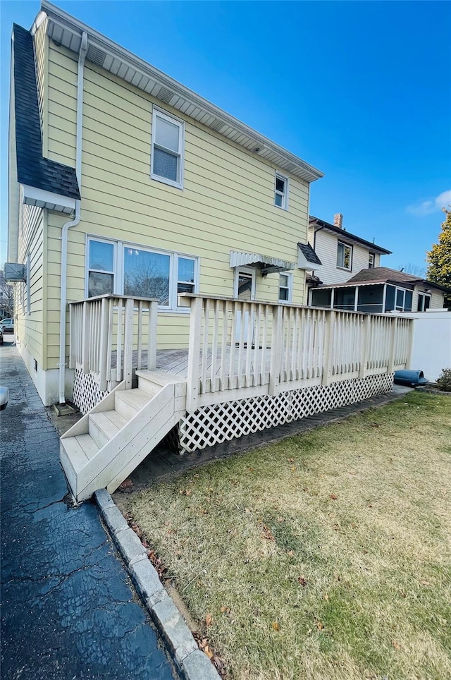 rear view of house with a lawn and a wooden deck