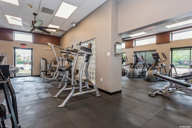 gym featuring ceiling fan, a paneled ceiling, and a towering ceiling