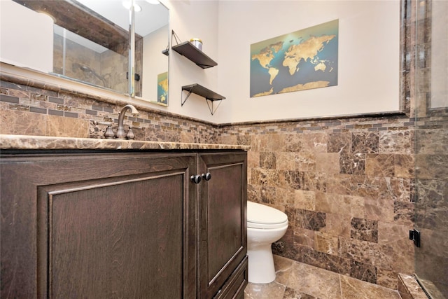 bathroom with tile walls, toilet, and vanity