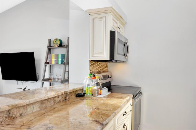 kitchen featuring tasteful backsplash, cream cabinetry, light stone counters, and stainless steel appliances