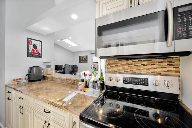 kitchen featuring appliances with stainless steel finishes, backsplash, light stone counters, and cream cabinets