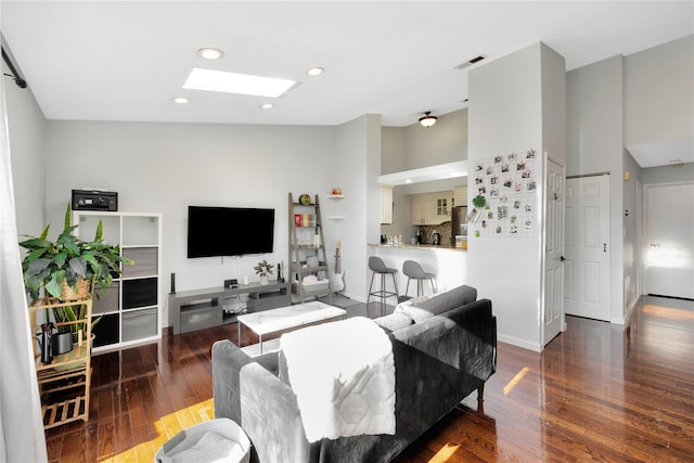 living room featuring dark wood-type flooring and a skylight