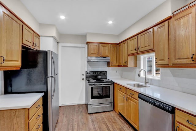 kitchen featuring sink, backsplash, light hardwood / wood-style flooring, and appliances with stainless steel finishes