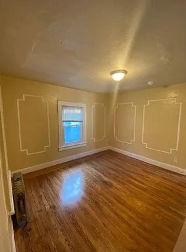 spare room featuring dark hardwood / wood-style flooring and radiator heating unit