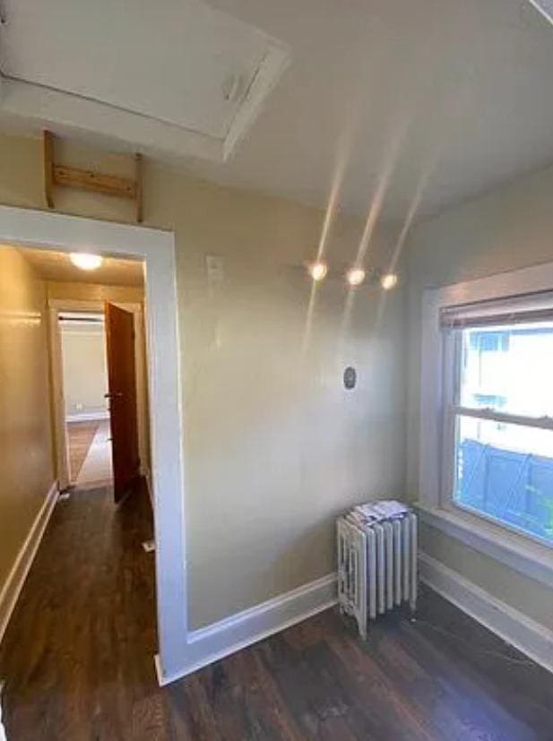 unfurnished room with radiator and dark wood-type flooring