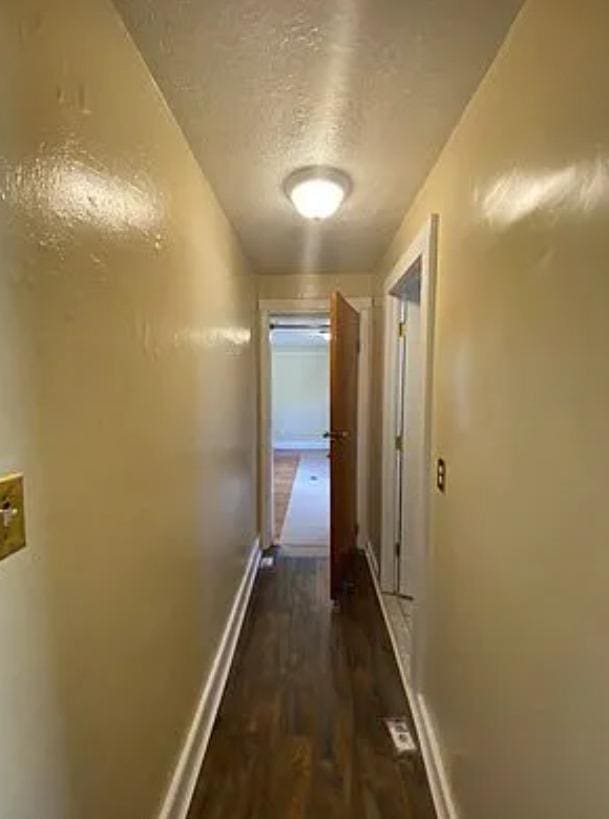 hall featuring dark wood-type flooring and a textured ceiling