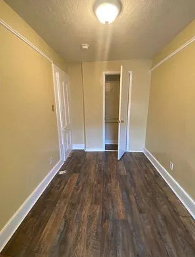 unfurnished bedroom with a textured ceiling, a closet, and dark hardwood / wood-style flooring