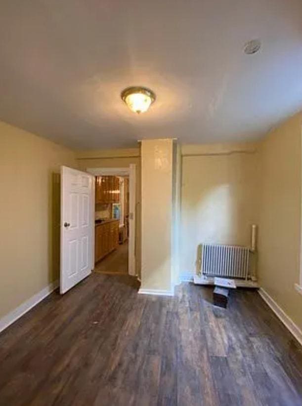 unfurnished room featuring dark hardwood / wood-style flooring and radiator heating unit