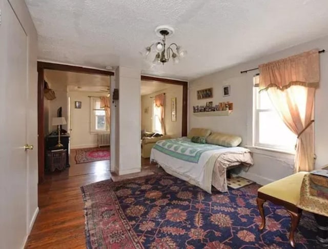 bedroom featuring a notable chandelier, a textured ceiling, dark hardwood / wood-style floors, and radiator heating unit