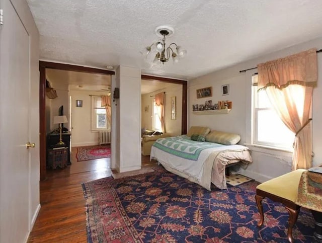 bedroom featuring a textured ceiling, a chandelier, hardwood / wood-style floors, and radiator heating unit