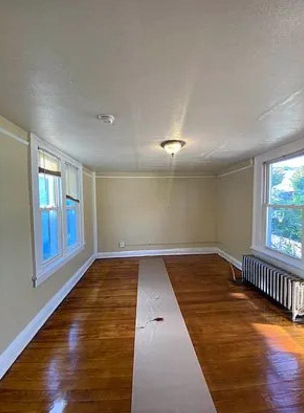 spare room featuring radiator and dark hardwood / wood-style flooring