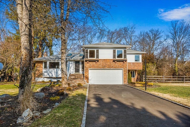 split level home featuring brick siding, fence, driveway, and an attached garage