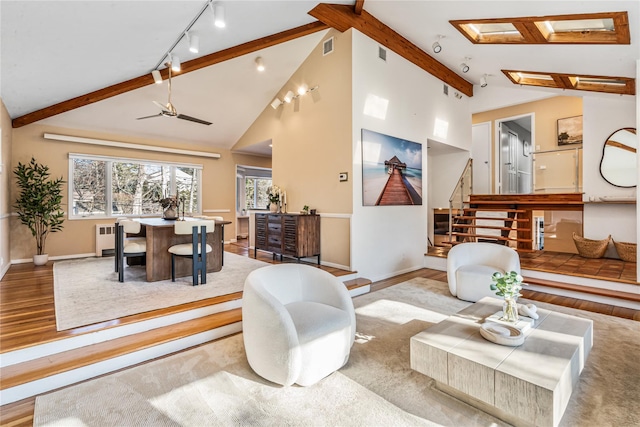 living room featuring beam ceiling, radiator, a skylight, and light wood-type flooring