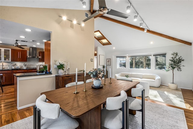 dining space featuring ceiling fan, wood-type flooring, and lofted ceiling with beams