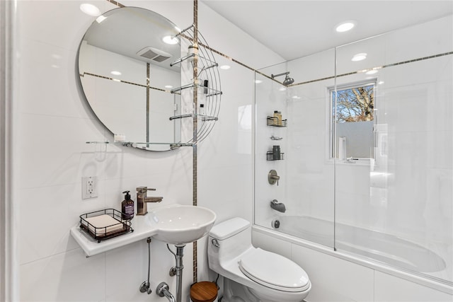 full bathroom featuring toilet, tile walls, enclosed tub / shower combo, and sink