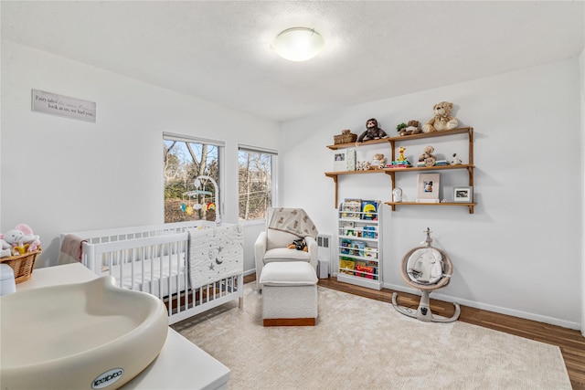 bedroom featuring a nursery area, sink, and wood-type flooring