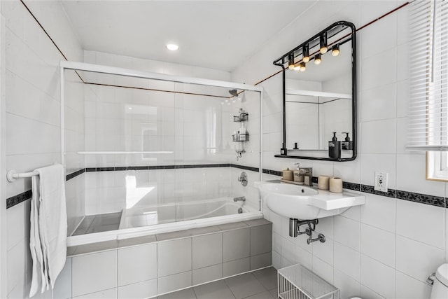 bathroom with tile patterned floors, tile walls, enclosed tub / shower combo, and toilet