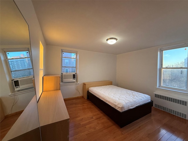 bedroom featuring radiator, cooling unit, and hardwood / wood-style floors