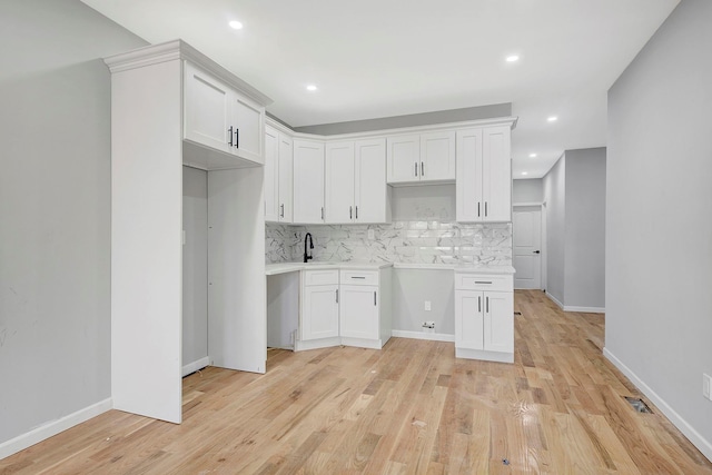 kitchen featuring decorative backsplash, light hardwood / wood-style floors, white cabinets, and sink