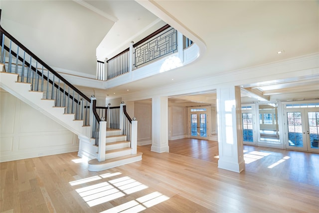 entrance foyer with crown molding, light hardwood / wood-style flooring, french doors, and decorative columns