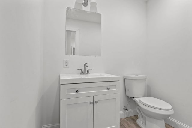 bathroom featuring toilet, vanity, and hardwood / wood-style floors