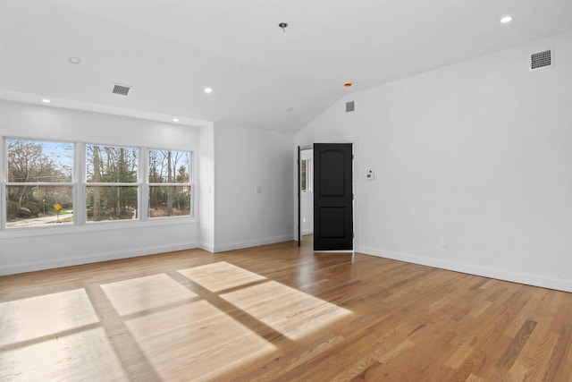 empty room with light wood-type flooring and vaulted ceiling