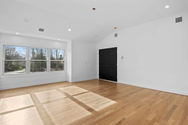 spare room featuring light wood-type flooring and vaulted ceiling