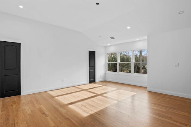 spare room featuring lofted ceiling and light wood-type flooring