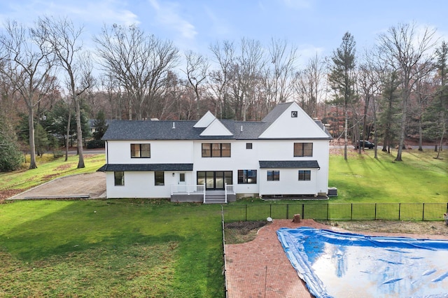 back of property featuring a covered pool, a lawn, and a patio