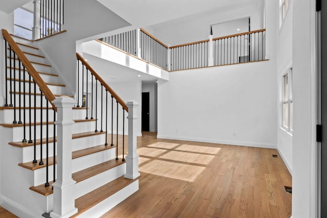 staircase featuring a towering ceiling and hardwood / wood-style floors