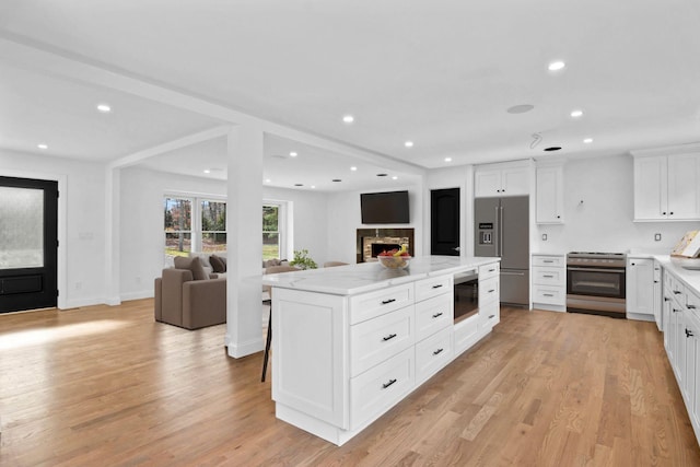 kitchen with light stone countertops, appliances with stainless steel finishes, a center island, and white cabinets