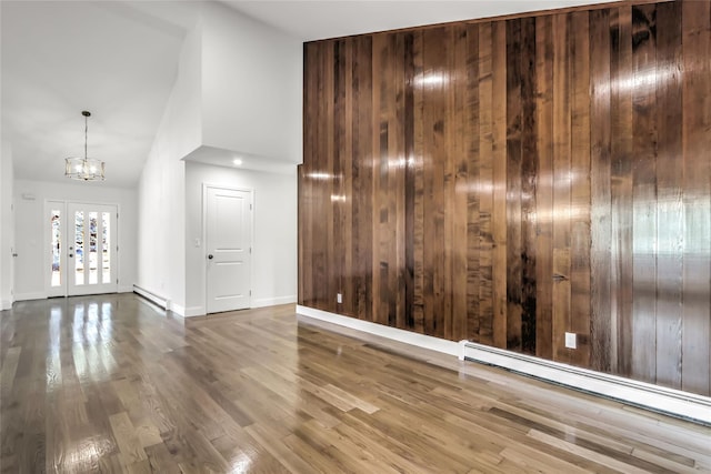 unfurnished room featuring a baseboard radiator, wood-type flooring, high vaulted ceiling, and french doors