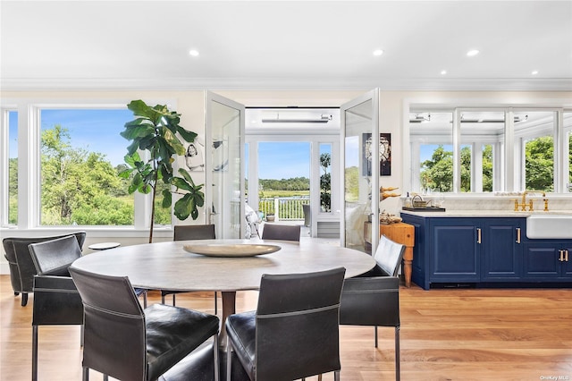 dining area featuring ornamental molding, light hardwood / wood-style floors, and sink