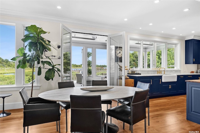 dining area featuring crown molding, sink, and light hardwood / wood-style flooring