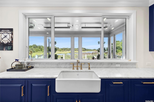 bar with blue cabinets, crown molding, sink, and light stone counters