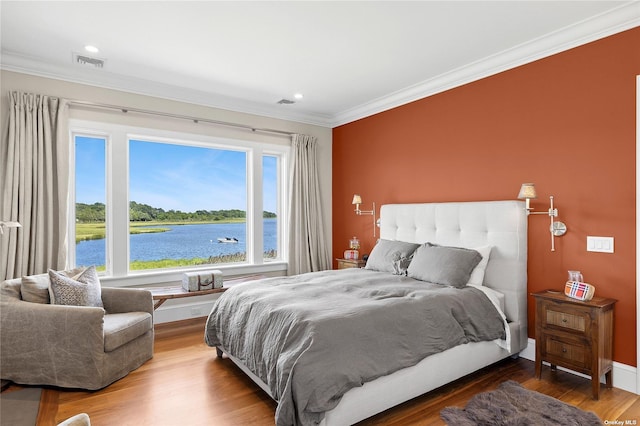 bedroom featuring a water view, crown molding, and hardwood / wood-style floors