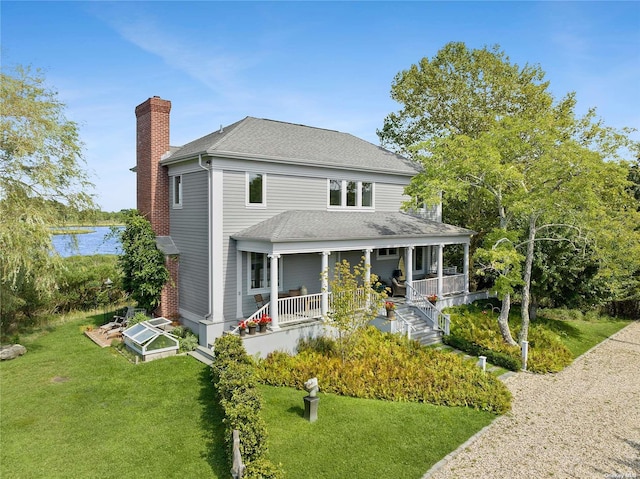 back of house with covered porch and a lawn