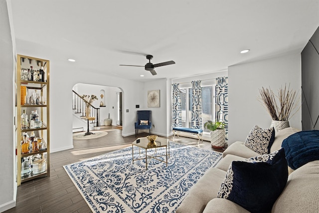 living room with baseboard heating, ceiling fan, and dark hardwood / wood-style flooring