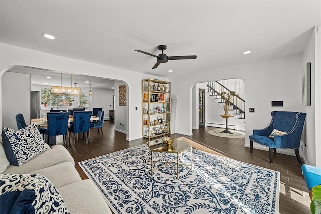 living room featuring ceiling fan with notable chandelier and dark wood-type flooring