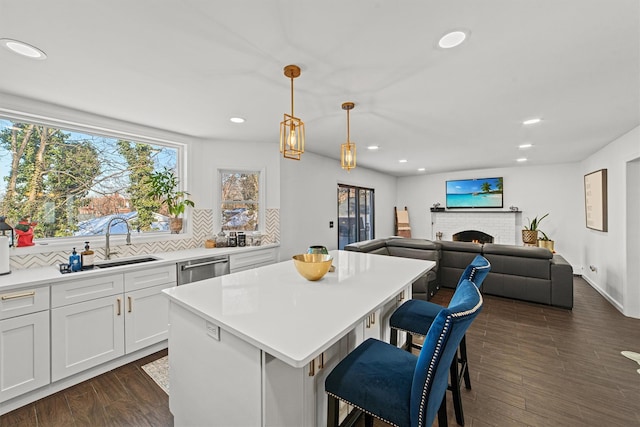 kitchen with a breakfast bar, hanging light fixtures, backsplash, a center island, and white cabinets