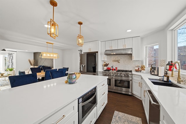 kitchen with pendant lighting, tasteful backsplash, sink, white cabinets, and stainless steel appliances