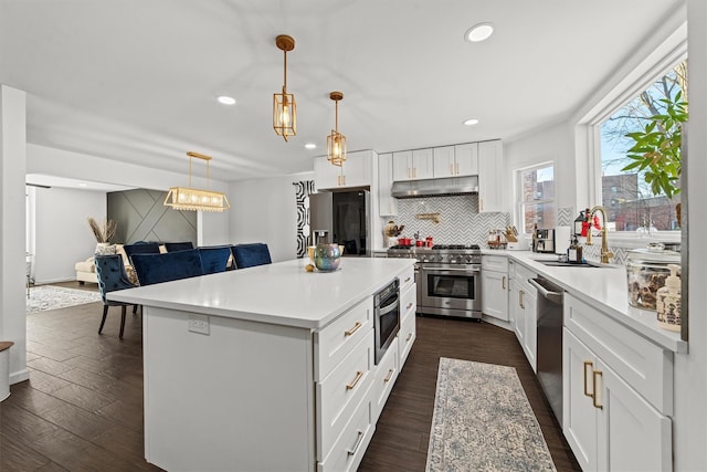 kitchen featuring sink, decorative light fixtures, a center island, stainless steel appliances, and white cabinets