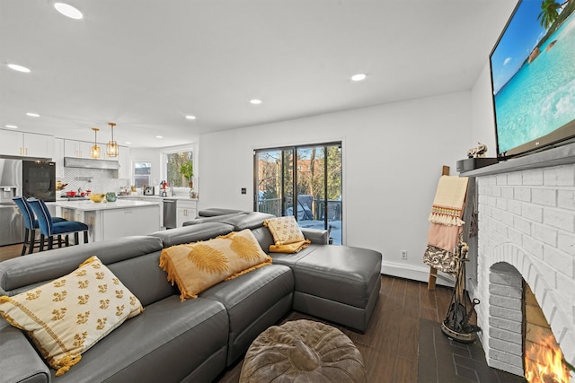 living room with a healthy amount of sunlight, a fireplace, and dark hardwood / wood-style flooring