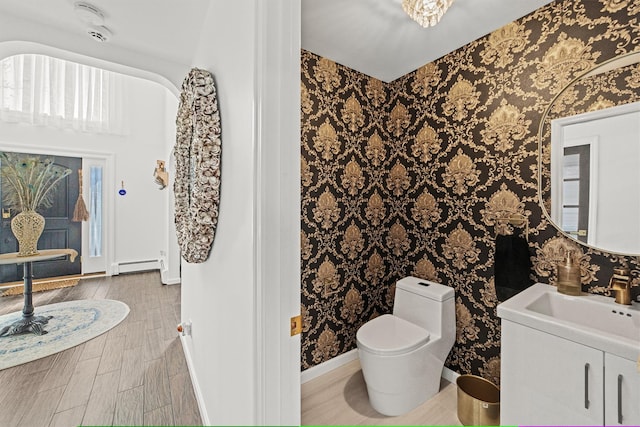 bathroom featuring wood-type flooring, sink, baseboard heating, and toilet