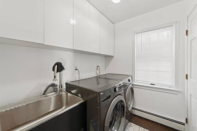 laundry room with dark wood-type flooring, sink, cabinets, baseboard heating, and washing machine and dryer