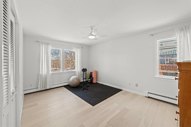 exercise room with a baseboard heating unit, light hardwood / wood-style flooring, and ceiling fan