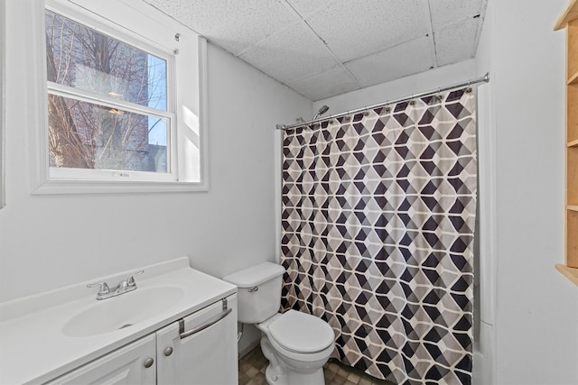 bathroom with walk in shower, a paneled ceiling, vanity, and toilet